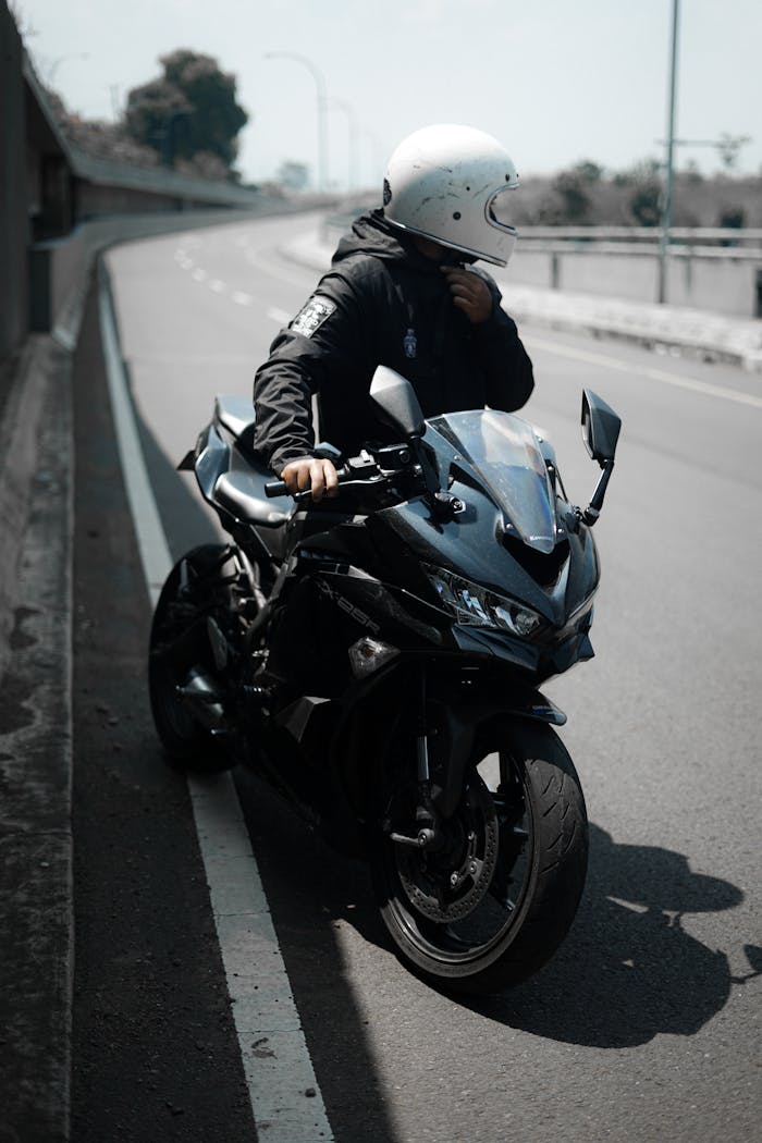 Motorcyclist in helmet parked on a deserted urban road, showcasing modern lifestyle.